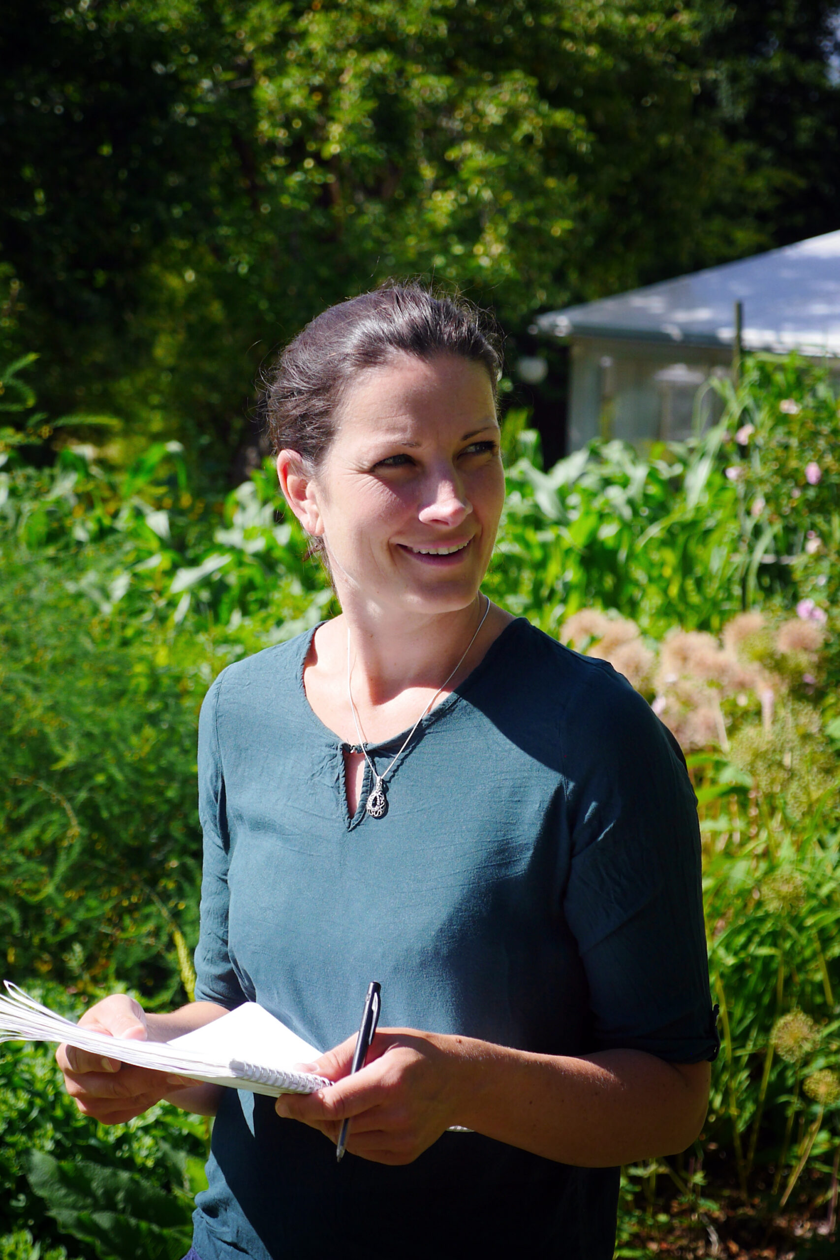 Ett porträtt på EcoTopics VD Lotta en solig dag utomhus med grönska i bakgrunden