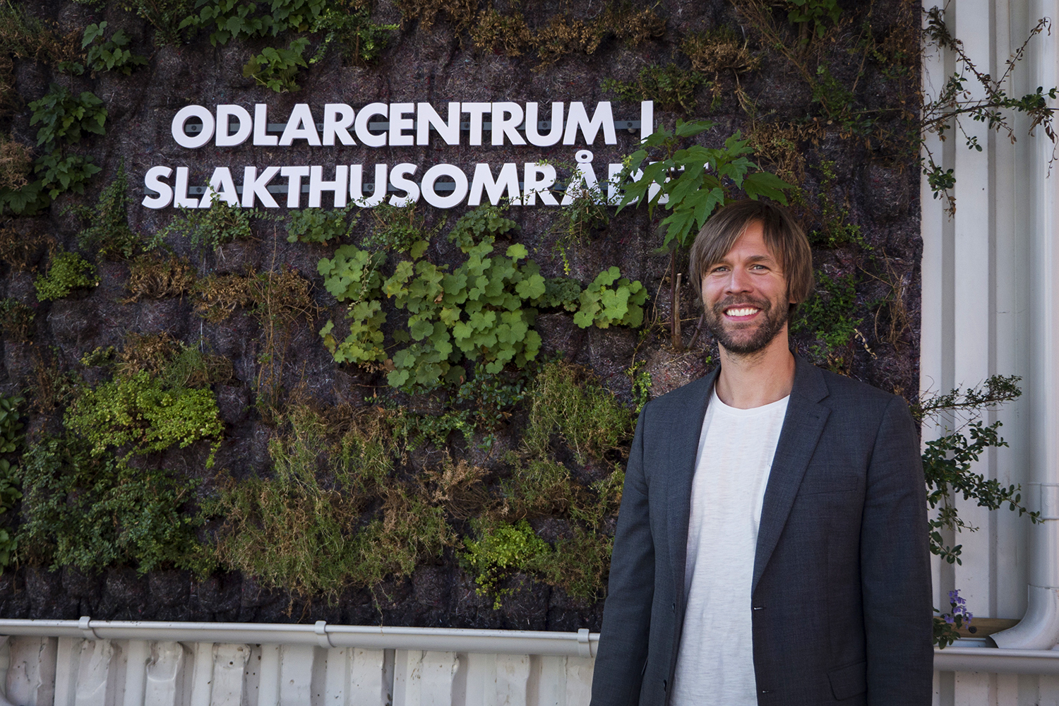 Mattias står utomhus framför en skylt i grönska som läser Odlarcentrum i slakthusområdet